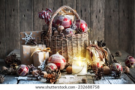 Christmas Composition with Gifts and Burning Candle. Basket, red balls, pine cones, snowflakes on Wooden Table. Vintage style