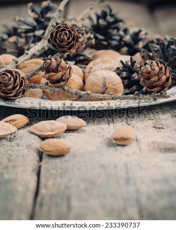 Christmas Natural Composition with Pine cones, Walnuts, Almonds, Nuts on Wooden Background, holiday decoration, toning