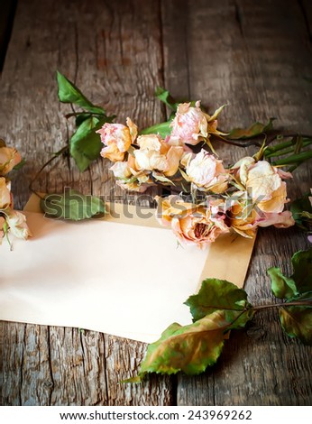Dry Pink Roses and Old Paper on Wooden Background, letter to memory