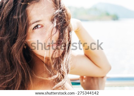 Beautiful young woman on the background of sea in sunlights. With Long Hair Blowing in the Wind