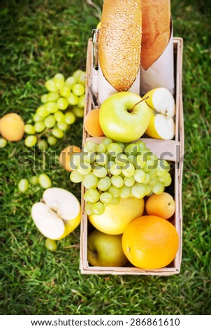 Fruits, Long loafs, Juice in Basket. Picnic on Green Grass, Top view, vertical image