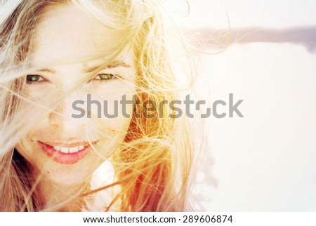 Portrait Of Happy Smiling Beautiful Woman with Hair Blowing in the Wind. in Sunlight. Warm Color Toned