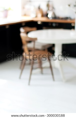 Blurred Background of Black, White Home Kitchen with Light Bokeh. Table and Chair on White Floor