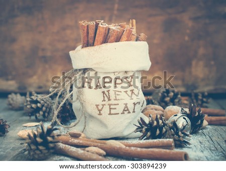 Cinnamon in a linen Bag with Embroidery Happy New Year and  other christmas ingredients, Pine cones, Walnuts. Toned Vintage Christmas Composition