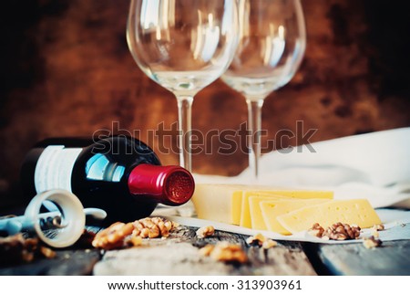 Still Life with Red Wine, Glasses, Walnuts, Cheese and Opener on Wooden Table. Rural Style