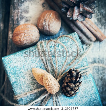 Christmas Holiday Box with Linen Cord, Decorative Snow, Almond, Natural Gifts on Wooden Background. Toned image. Vintage style