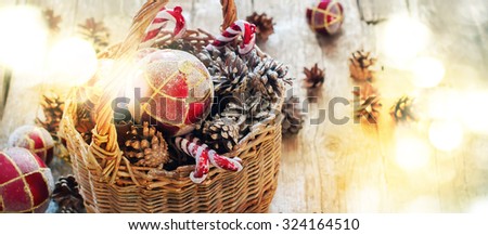 Bright Light Spots as Festive effect on Rhoto with Christmas  Fir Tree Toys in Basket, Red balls, Pine cones, Sweet Candy Toys on Wooden background