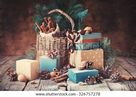 Festive Gifts with Boxes, Coniferous, Basket, Cinnamon, Pine Cones, Walnuts on Wooden Background. Christmas Presents Toned in Vintage Style