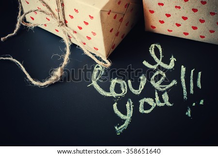Message I Love You and Boxes in Hand made Paper with Hearts Pattern on Dark Background. Toned
