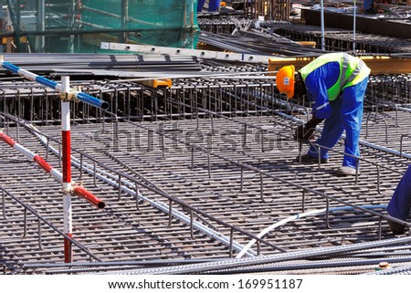 DOHA, QATAR - NOV 13: A steel fixer carefully tying reinforced steel bars in position in preparation for the construction of a concrete slab on Nov 13, 2013 in Doha, Qatar.