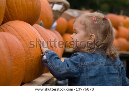 Cute little girl picking halloween pumpkin at farmer\'s market