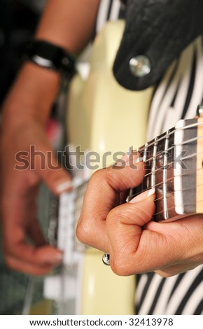 woman plays an electric guitar, images is selective focus on the neck hand