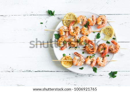 Grilled shrimp skewers. Seafood, shelfish. Shrimps Prawns skewers with spices and fresh herbs on white wooden background, copy space. Shrimps prawns brochette kebab. Barbecue srimps prawns.