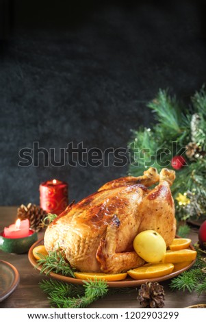 Roasted Christmas Chicken or Turkey for Christmas Dinner. Festive decorated wooden table for Christmas Dinner with baked chicken, copy space.