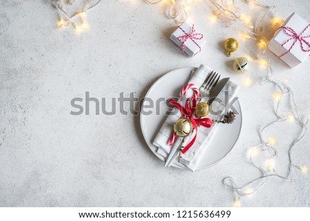 Christmas Table Setting with  lights and gift boxes on white table, copy space. Christmas dinner, party design, concept.