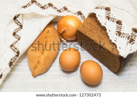 Bread, brown eggs, patty and onion over linen tablecloth. Natural simple food. Peasant lunch.