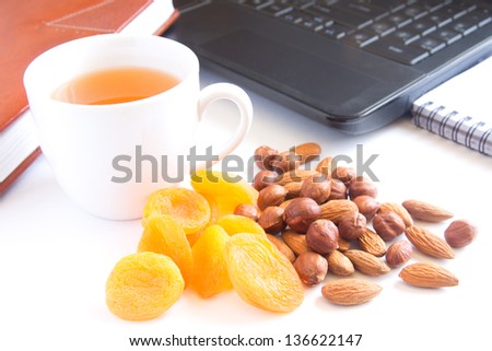 Healthy quick snack (lunch) in office. Cup of tea, dry apricots (fruits) and nuts.
