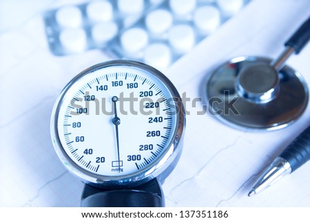 Stethoscope, blood pressure monitor close up, pills and pen on electrocardiogram chart. Medical concept for cardiology, examination, screening, blood pressure.