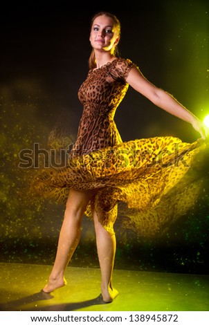 Beautiful happy sensual pretty woman wearing long brown dress spinning in magic dance in the dark (studio)