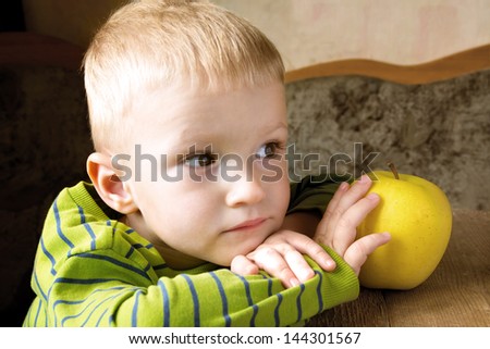 Child dreaming and thinking at home with yellow apple, close up portrait with copy space.