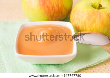 Fresh homemade applesauce (apple puree, babyfood) with green apples and spoon close up, horizontal, vegetarian