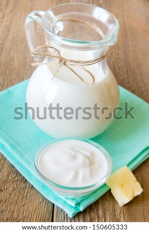 Calcium dairy fresh products set: milk, sour cream, cheese on napkin and wooden table, close up, vertical