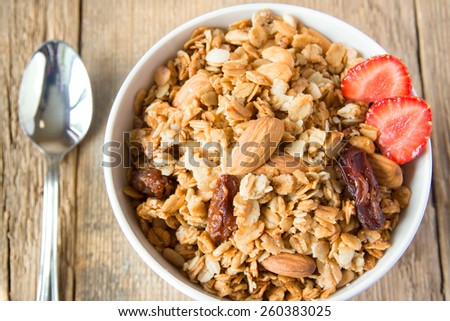 delicious and healthy wholegrain muesli breakfast, with lots of dry fruits, nuts and grains close up, horizontal, on wooden table with spoon