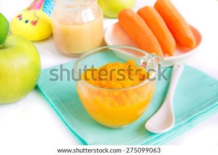 Baby food (pureed carrot and apple) close up on white table