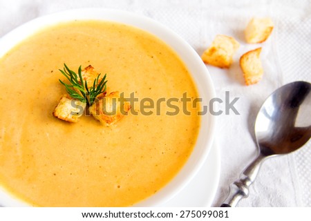 Cream soup with croutons and dill  on white napkin, horizontal close up