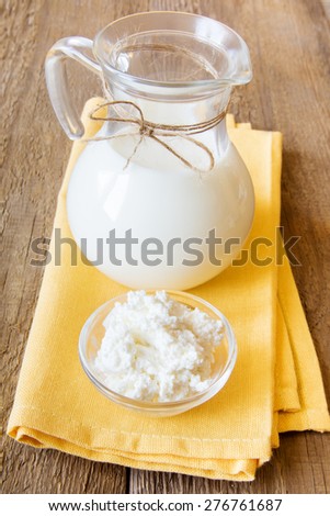 Fresh dairy products: milk and cottage cheese  on napkin and wooden table, close up, vertical.