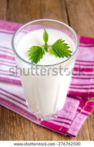 Fresh plain homemade yougurt (yogurt, youghurt, kefir, ayran) in glass with mint over rustic wooden table