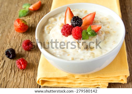 Oatmeal porridge with berries on rustic wooden table