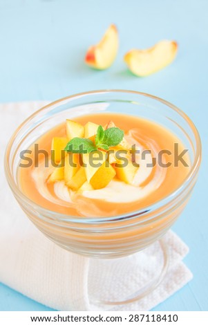 Peach dessert (mousse) with yogurt and mint on blue background