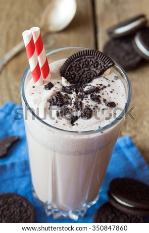 Homemade milkshake (chocolate smoothie) with cookies on rustic wooden table close up