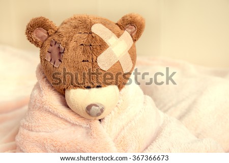 Sick teddy bear with patch in bed