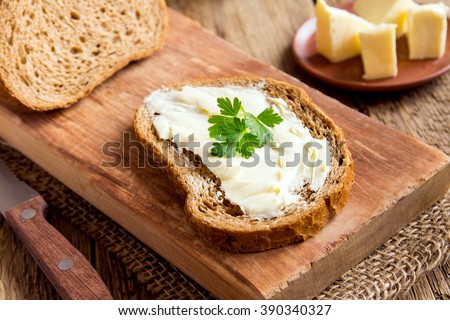 Butter and bread for breakfast, with parsley over rustic wooden background close up