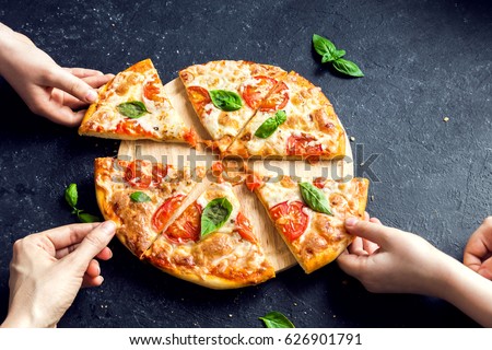 People Hands Taking Slices Of Pizza Margherita. Pizza Margarita and  Hands close up over black background.