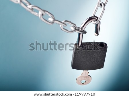 Unlocking a padlock securing two metal chains with blue background