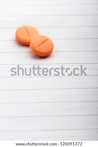 Two pills on lined paper with copy space for a short note