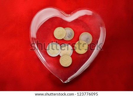 Charity. Glass heart with Euro coins inside representing charity or love of money