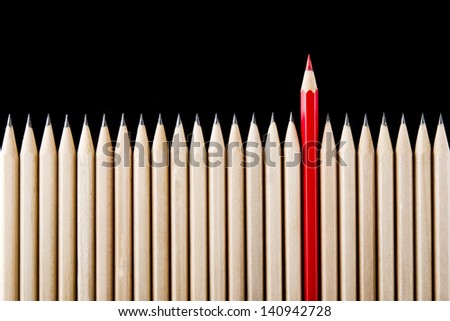 One red pencil standing out from the row One red pencil standing out from the row