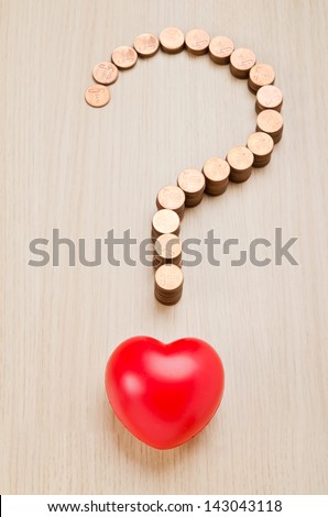 Question mark sign made out of coins and red heart