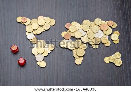 Financial risk. Office desk with world map made of money coins and two red dices