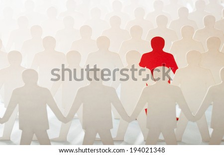 Red paper cut-out figure standing out among other white paper cuts