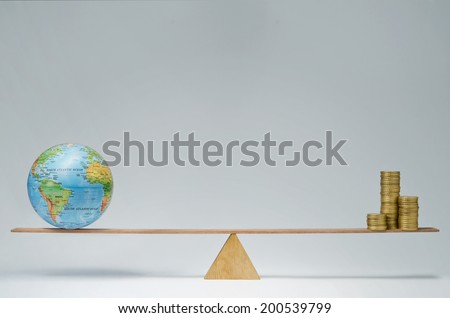 World globe and money coins stack balancing on a seesaw