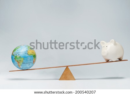 World globe and piggy bank balancing on a seesaw