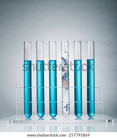 Rolled up Euro paper banknote in a test tube rack representing the costs of medical research