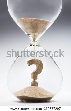 Future uncertainty. Question mark made out of falling sand inside hourglass