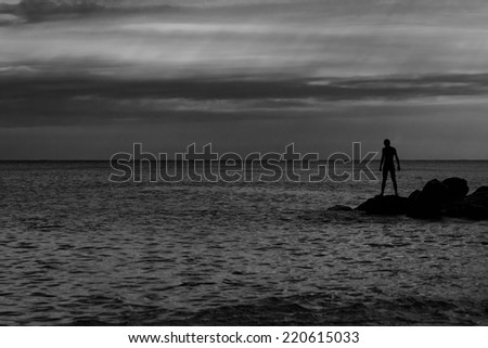 Photograph of the man on the rocks. Silhouette. Black and white photo.