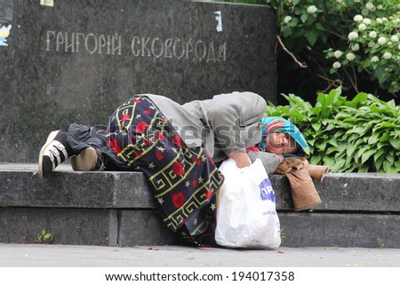 Kiev, Ukraine May 20, 2014: A homeless woman sleeping near the monument to Grigory Skovoroda on a granite slab.